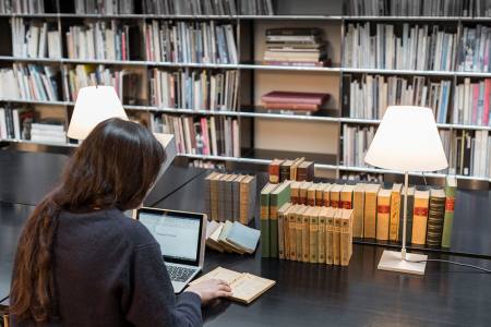 Une chercheuse consulte des documents anciens en salle de lecture