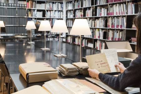 Une chercheuse consulte des documents anciens en salle de lecture